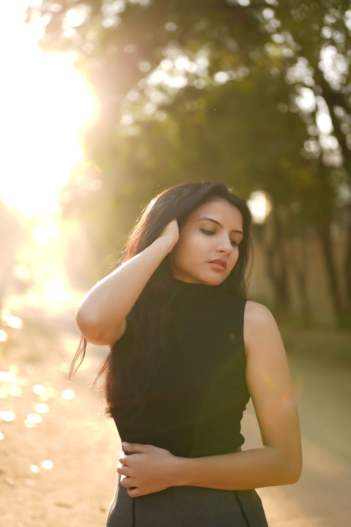 Woman with hand in her hair, backlit by low sun
