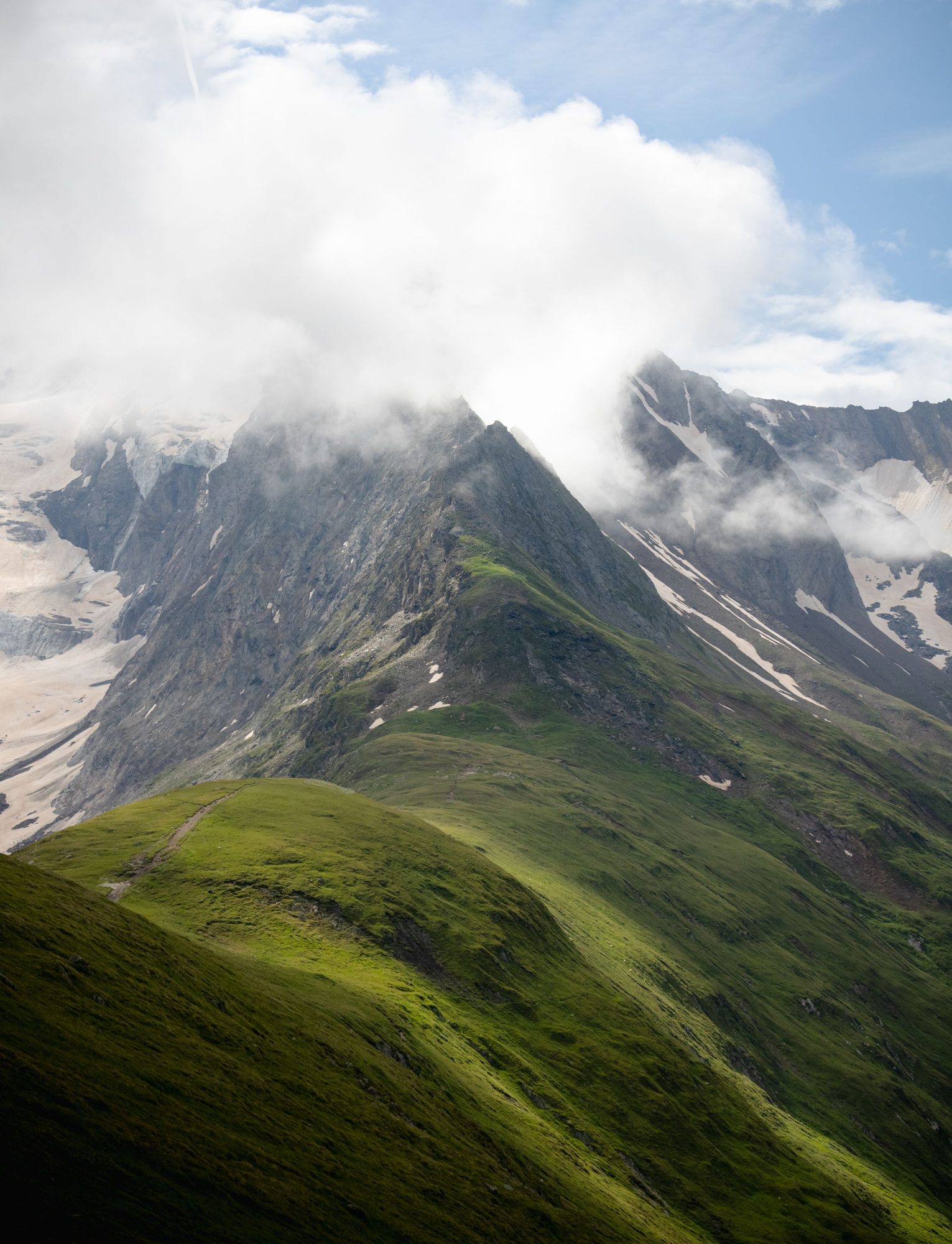 Green alpine valley under drifting cloud